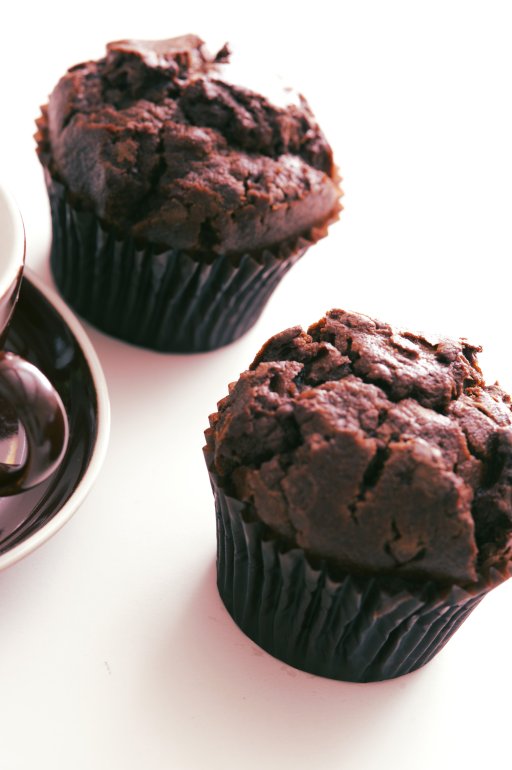 Tilted angle view on two freshly baked chocolate muffins on white table with subtle set down shadow