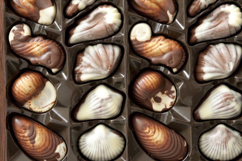 Box of packaged shell-shaped chocolate candy in white and milky chocolate as a gift for a loved one or celebration, close up overhead view