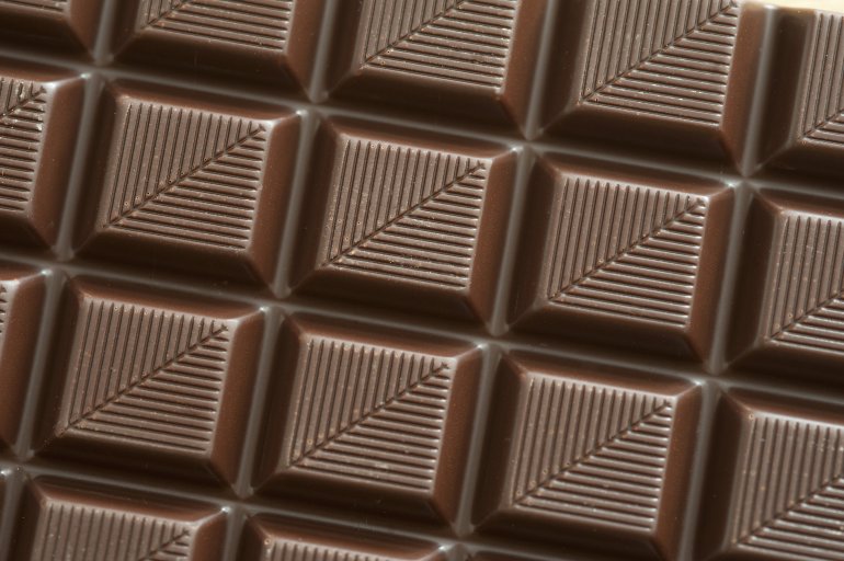 Bar of dark chocolate with decorative pattern of diagonal lines in a close up full frame texture and pattern