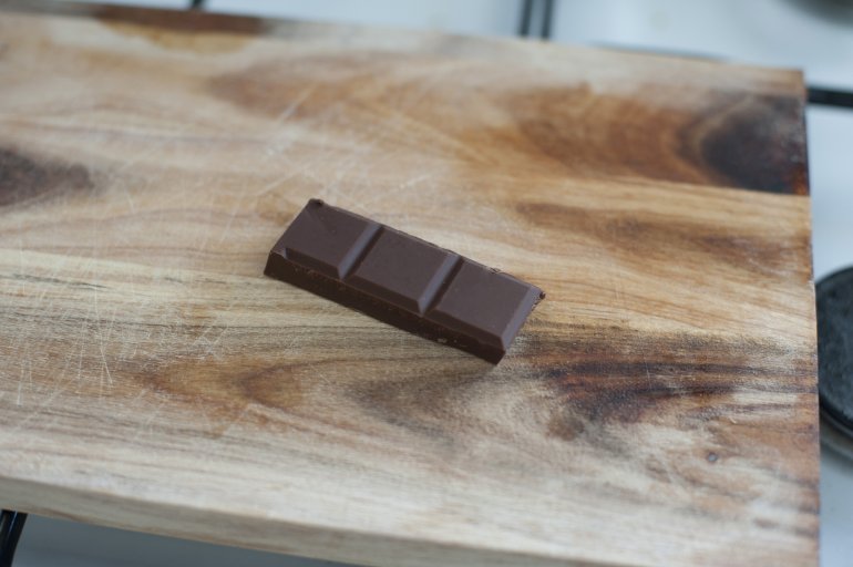 First person perspective view on dark baking chocolate squares bar in three sections over cutting board