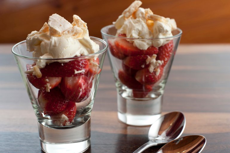 Strawberries and whipped cream dessert in two tall glasses for a delicious fruity sweet