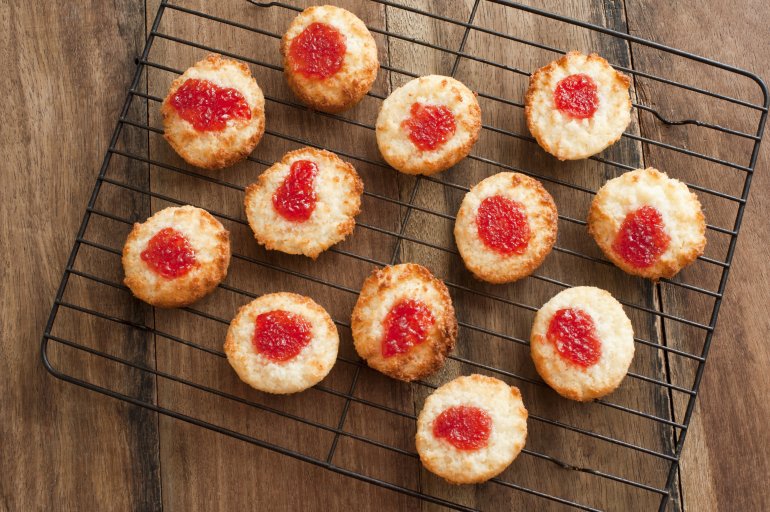 Rack of cooling freshly baked coconut drop cookies topped with strawberry jam viewed from the top