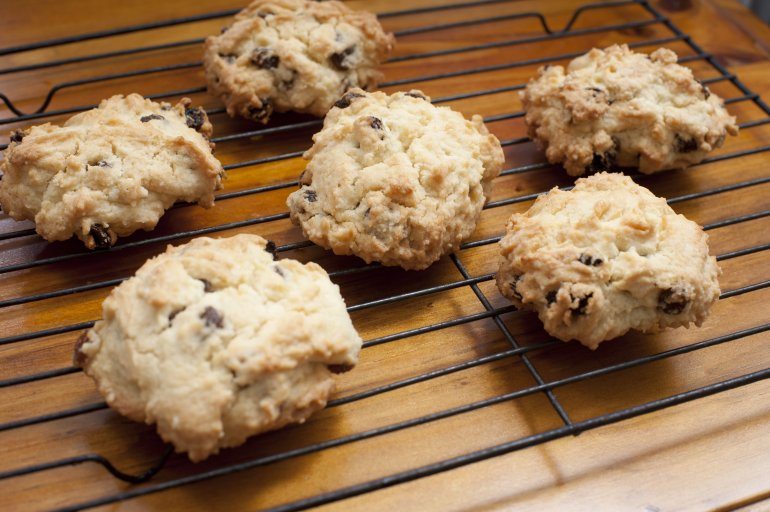 Five delicious rock cake type cookies with dates, raisins or chocolate pieces on oven rack over wooden table