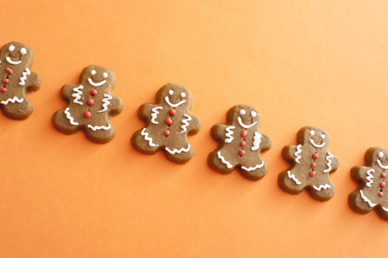 Single line of smiling gingerbread men cookies with white and red candy decorations detailing the face, arms and legs