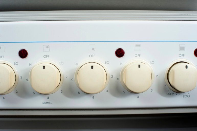 Row of control dials and thermostats on an electric cooker in a domestic kitchen