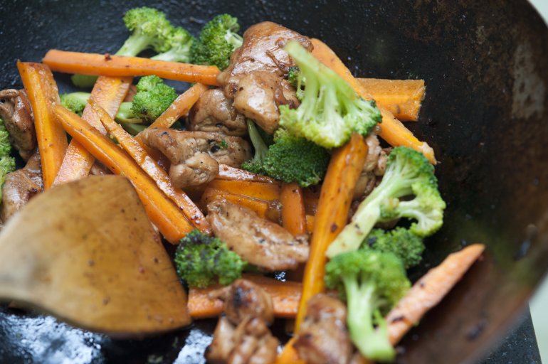 Cooking delicious Asian stir fry with an assortment of diced fresh vegetables frying in hot oil in a wok or pan