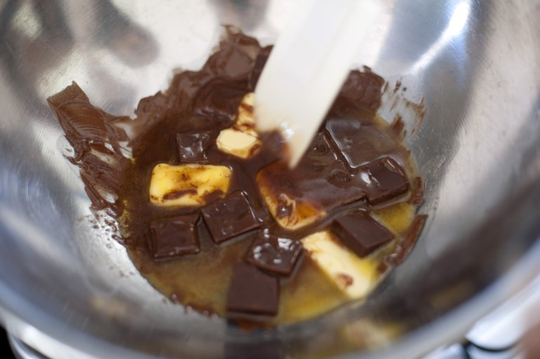 Dollops of butter and chocolate melting in a stainless steel mixing bowl bain marie, a concept of baking and food preparation