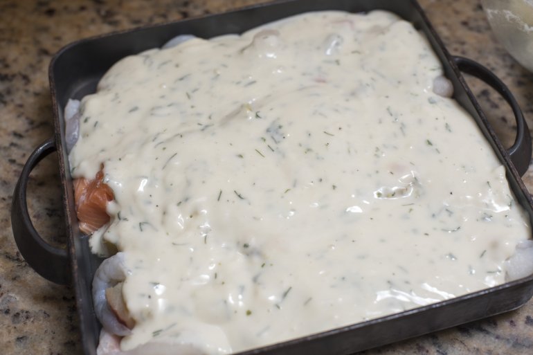 Delicious homemade seafood pie with creamy sauce topping over fish fillets ready in a baking tray