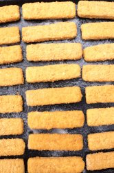 Frozen fish fingers laid out for baking