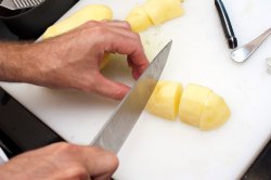 Man cutting peeled potatoes