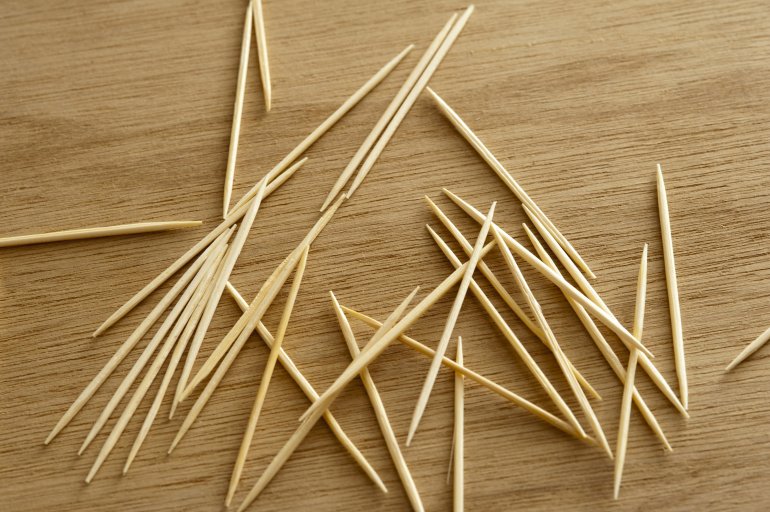 Randomly scattered toothpicks or cocktail sticks on a wooden table viewed from above