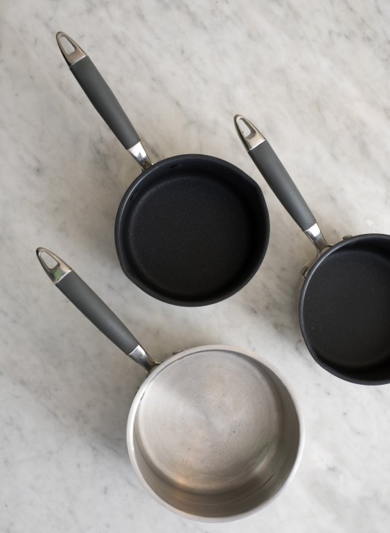 Three empty clean metal pots or saucepans Three empty clean metal pots or saucepans viewed from above on a mottled grey surface in a food and cookery concept