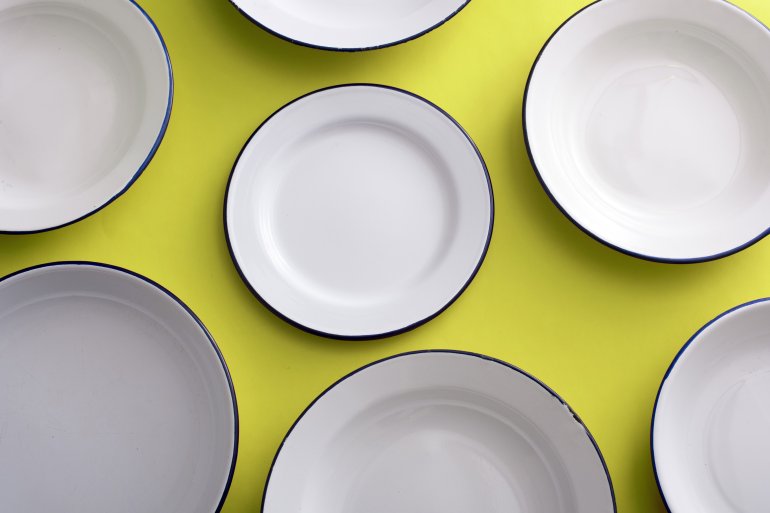 White metal enamel plates arranged on a colorful yellow background viewed from overhead in a full frame view