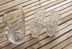 Clean transparent glass jug and four tumblers