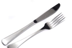 Silver knife and fork diagonally on white