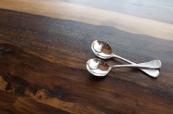 Two silver soup spoons on wood with copy space