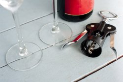 Corkscrew bottle opener alongside wine glasses
