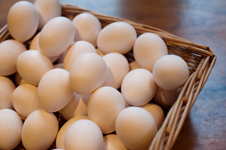 Farm fresh hens eggs displayed in a wicker basket at a farmers market for a healthy breakfast or to use as an ingredient in cooking and baking