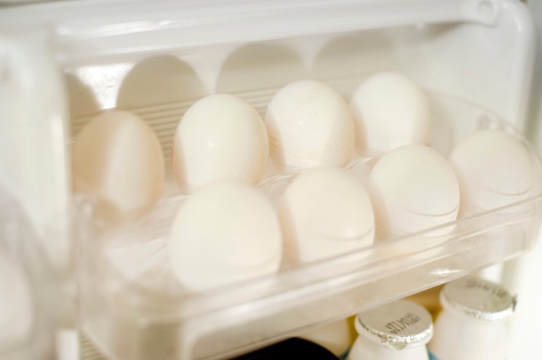 Tray of farm fresh white eggs in the the door of a fridge to be used as a healthy source of protein in cooking