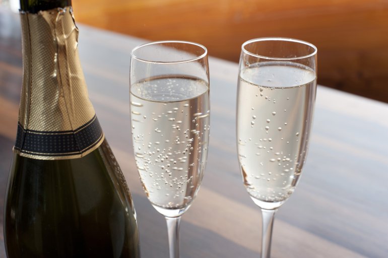 Two elegant flutes of sparkling champagne alongside a champagne bottle to celebrate a special occasion or romantic tryst