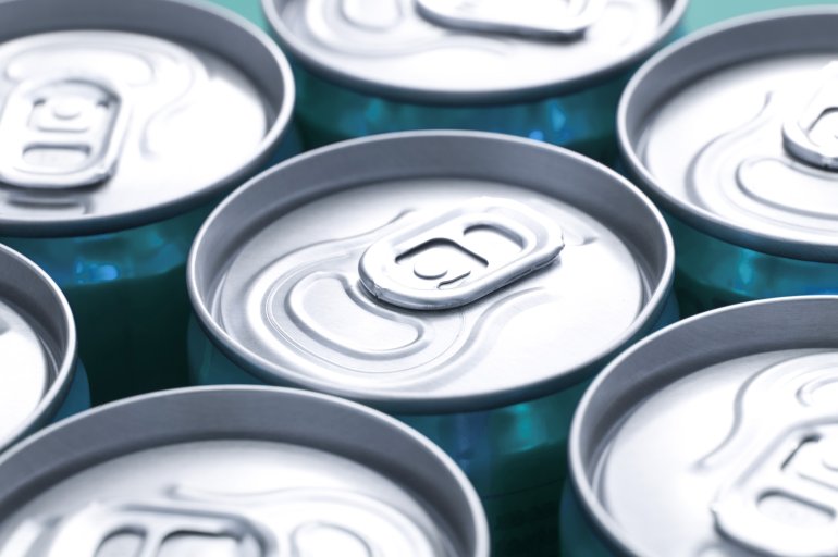 Close up view of plain silver ring pulls on closely arranged beverage cans with focus to one can in the centre