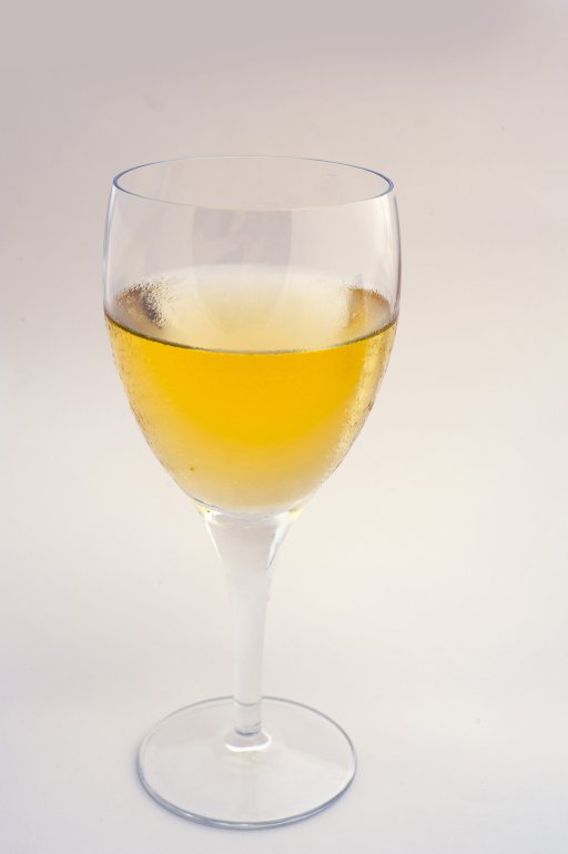 Close up side view of a single glass of white wine over a grey studio background with copyspace