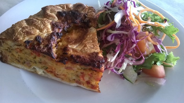 Close Up Still Life of Healthy Lunch Consisting of Piece of Egg Pie Quiche on White Plate with Fresh Shredded Salad on the Side