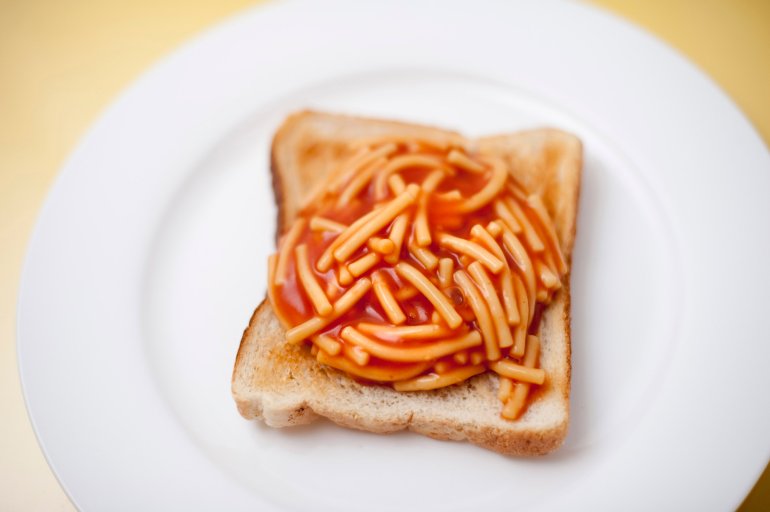 Quick childhood snack of tinned spaghetti or noodles in tomato sauce served on a slice of white toast, high angle view