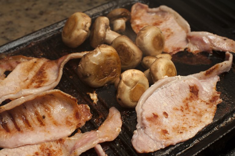 Close-up of mushrooms and pork cooking on grill