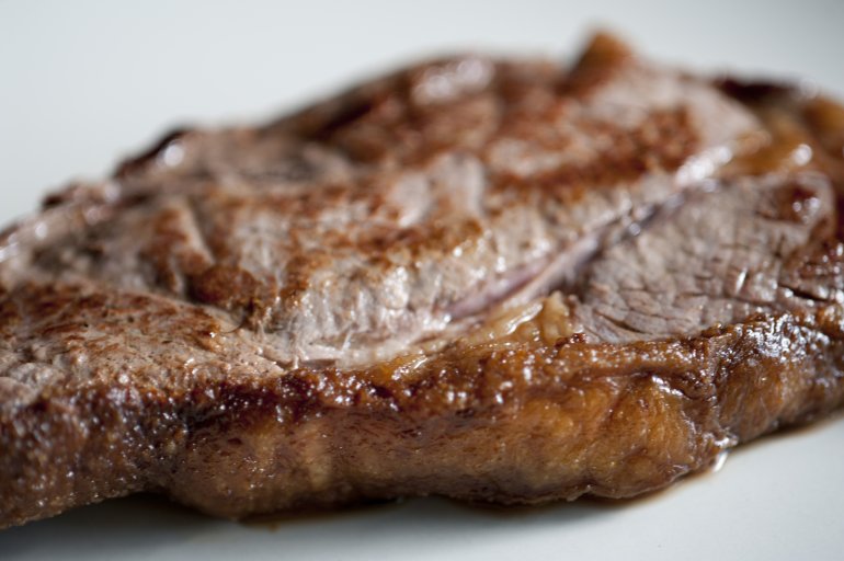Fatty steak with a close up view of the cooked oily fatty rind on a portion of beef rump steak