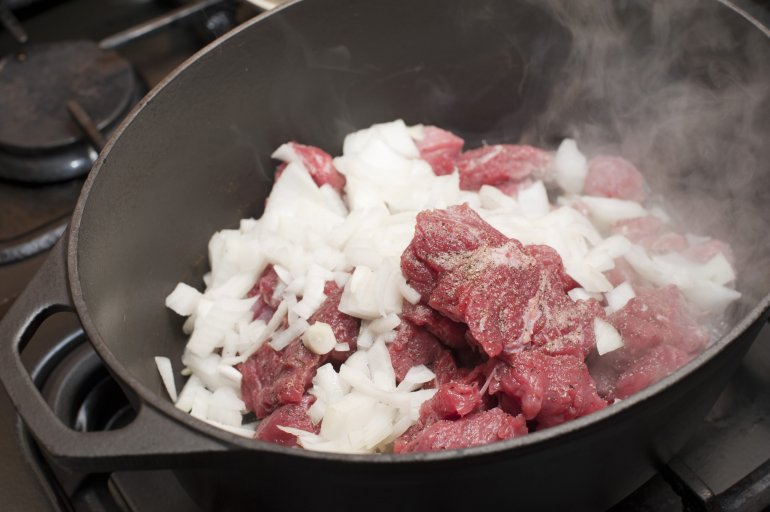 Moment of preparing beef with onion in saucepan