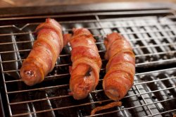 Sausage and bacon rolls on a grill in close up