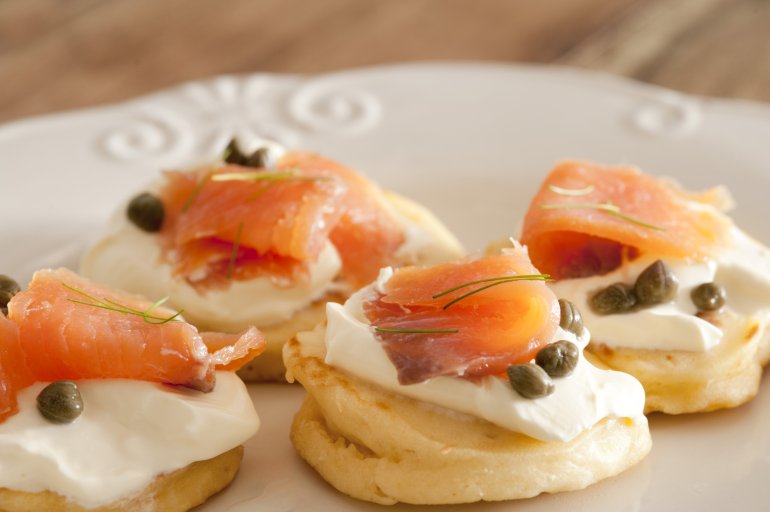 a plate of smoked salmon and cream cheese blini canapes