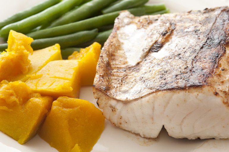 Close up on lean healthy meal of baked mackerel slice beside cubed squash and green string beans
