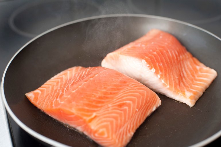 Two fresh salmon fillets in a frying pan in preparation of a delicious gourmet seafood dinner