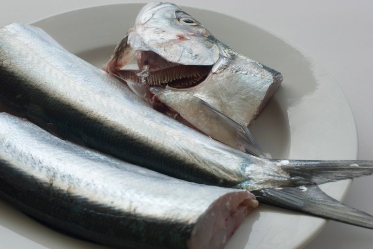 Preparing fresh raw fish with two fish on a plate, one with the head severed and placed alongside