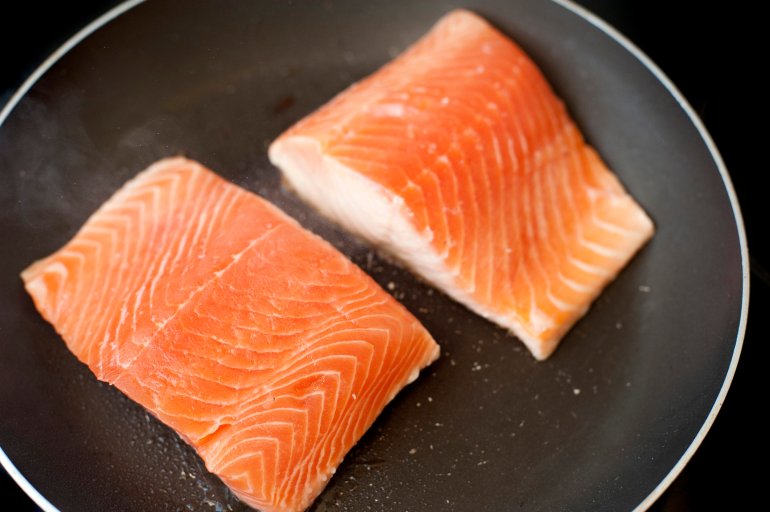 Overhead view of two raw salmon fillets in a pan waiting to be pan seared or fried for a delicious seafood meal