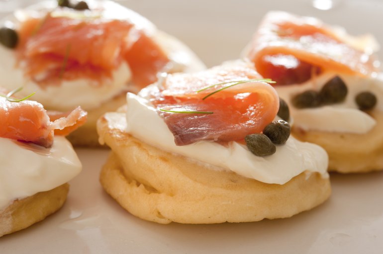 Close up of smoked salmon with capers and creme party food appetizers with strong light source from the top