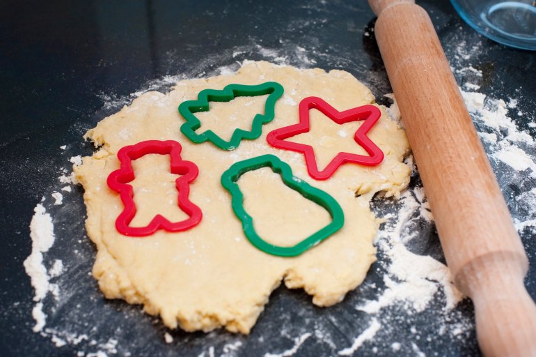 Rolled pastry dough with cookie cutters in traditional Christmas shapes for making seasonal cookies and biscuits