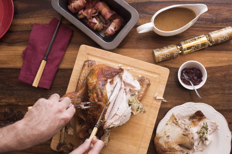 Man carving and serving the Christmas roast turkey viewed from above in a first person POV