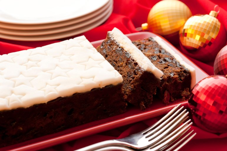 Traditional fruity Christmas cake with decorative star icing sliced and served on a platter on a festive Christmas table with ornaments