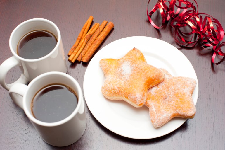 High angle view of two mugs of black espresso coffee served with Christmas doughnuts in a traditional star shape