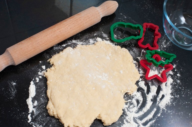 Overhead view of rolled pastry for baking Christmas biscuits or cookies with traditional cookie cutters in festive seasonal shapes