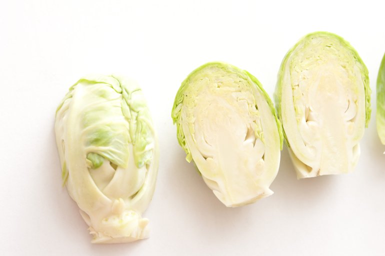 A close up of halved brussel sprouts on a white background.