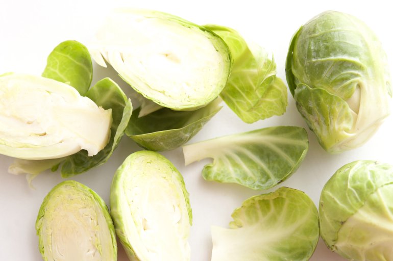 A close up of sliced brussel sprouts on a white background with copy space.