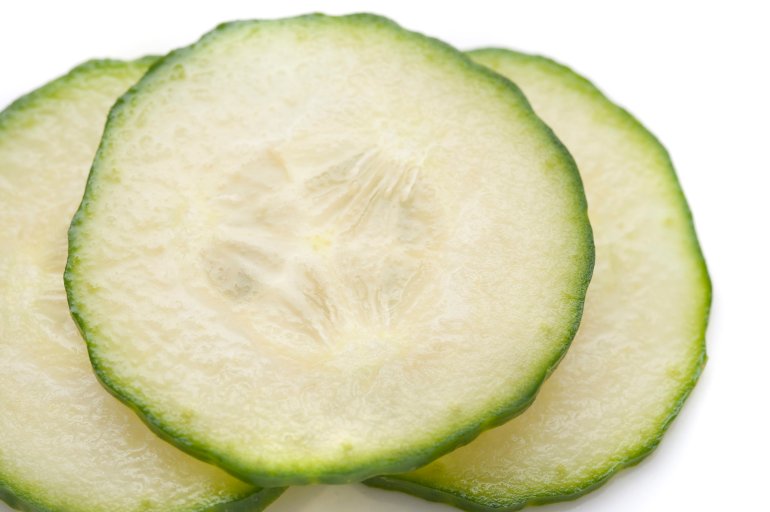 Close up of thinly sliced cucumber showing pip, pulpy flesh and rind detail for use as a salad ingredient