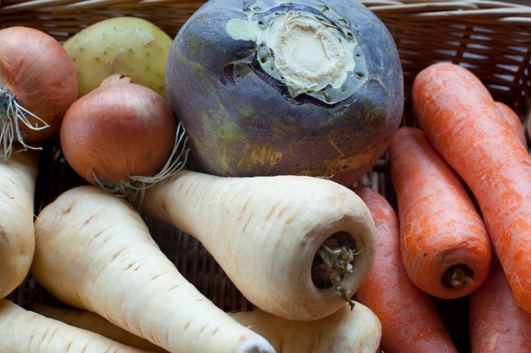Collection of root vegetables with fresh uncooked turnips, carrot and parsnip in a wicker basket at farmers market