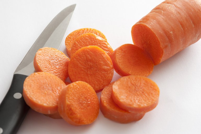 Close-up of cut carrot and knife on white background