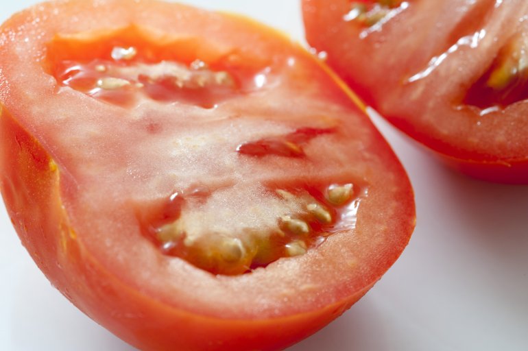 Fresh halved ripe tomato viewed close up at an oblique angle to show the juicy texture of the pulp