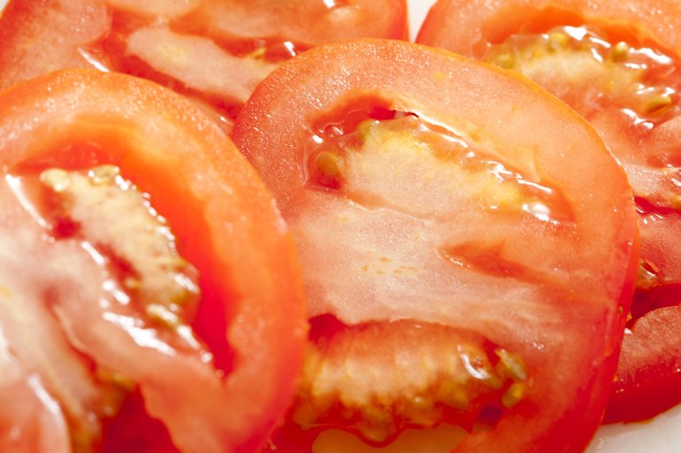 Close up macro view of juicy ripe red fresh raw tomato slices showing the texture of the pulp in a full frame view